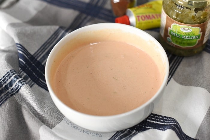 Thousand Island Dressing whisked together in a small white bowl with the ingredients in the background.