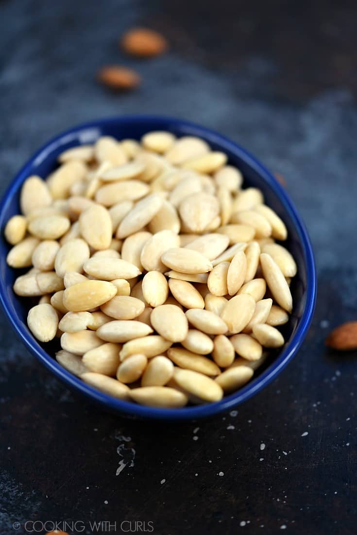 Blanched whole almonds in an oval, blue bowl.