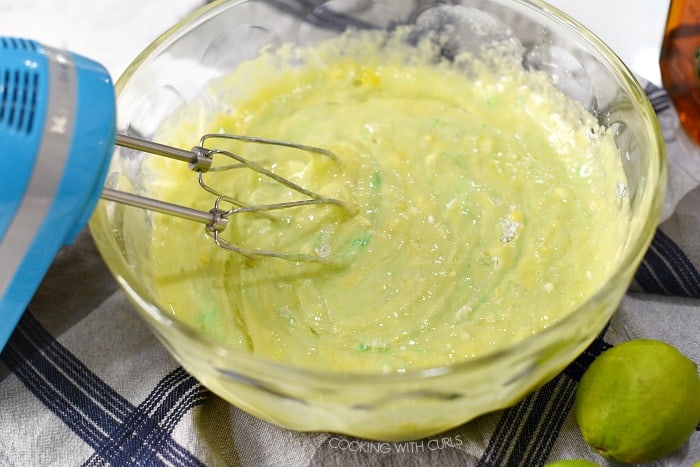 Margarita cake ingredients stirred together in a large glass bowl. 