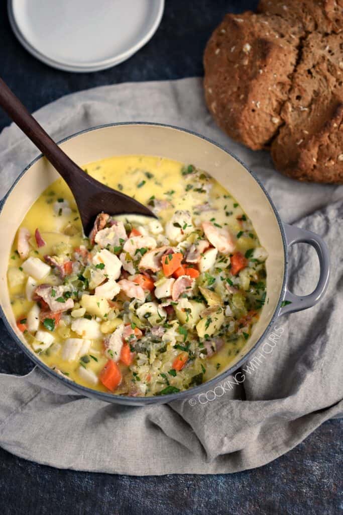 Looking down on Creamy Seafood Chowder with a loaf of Irish Brown Soda Bread in the background.