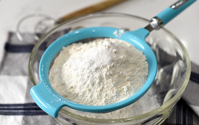 Flour, baking powder and salt in a sifter over a large glass bowl.