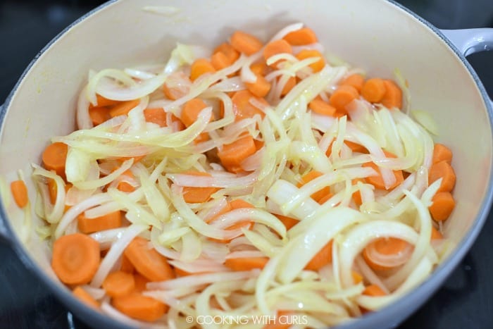 Onion and carrot slices cooking in a casserole pan. 