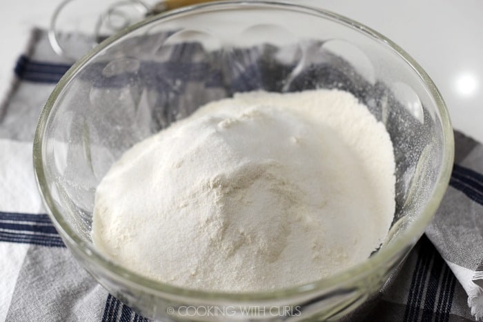 Sugar added to the sifted flour mixture in a large glass bowl. 