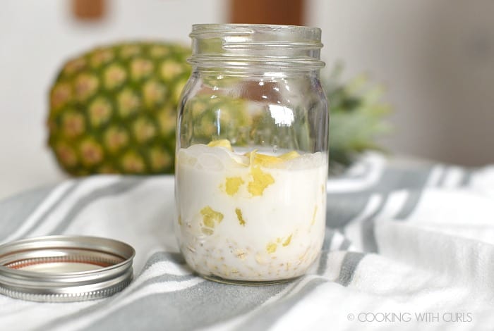 Coconut milk, oats and pineapple chunks in a glass mason jar. 