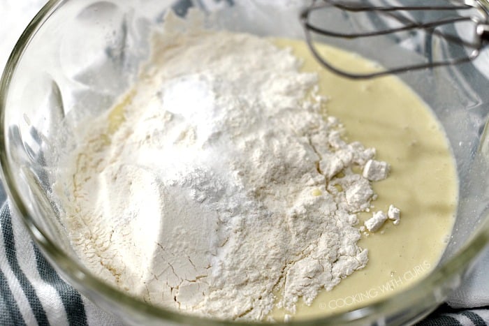 Flour, salt, baking soda and powder added to the liquid ingredients in a glass bowl. 