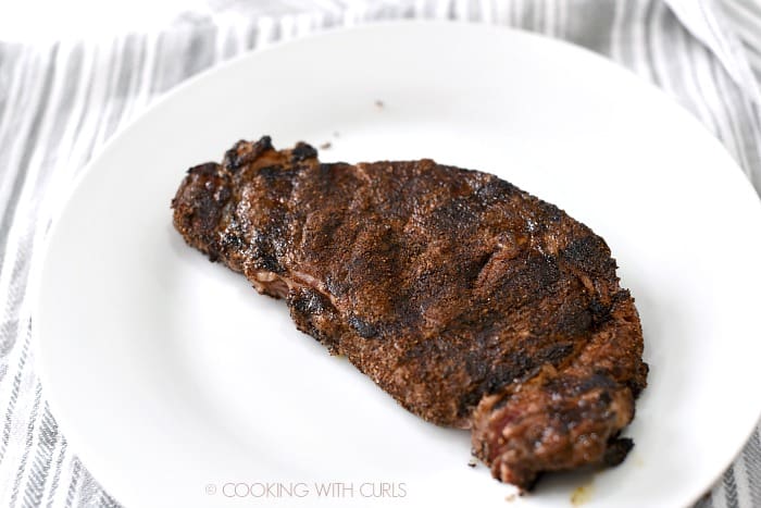 Grilled, spice rubbed steak on a large white plate. 