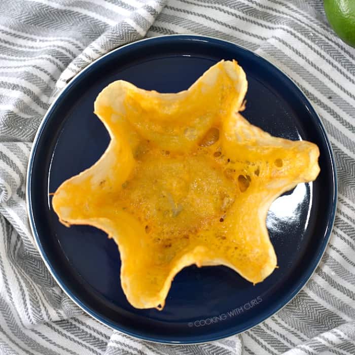 Melted cheese covered tortilla shell on a dark blue plate. 