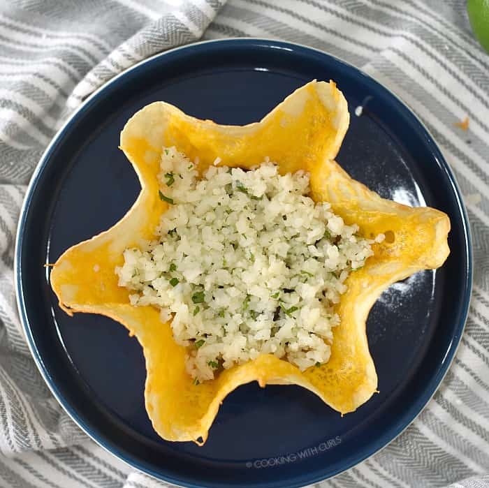 Melted cheese topped tortilla shell with cilantro lime rice on a dark blue plate. 