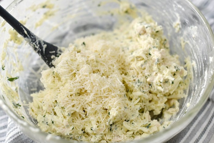 Parmesan cheese stirred into ricotta mixture in a large glass bowl. 