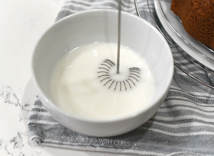 Pina Colada glaze in a small white bowl whisked together with a wire whisk. 