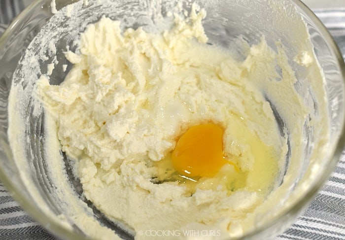 Ricotta cheese and one egg in a large glass bowl. 