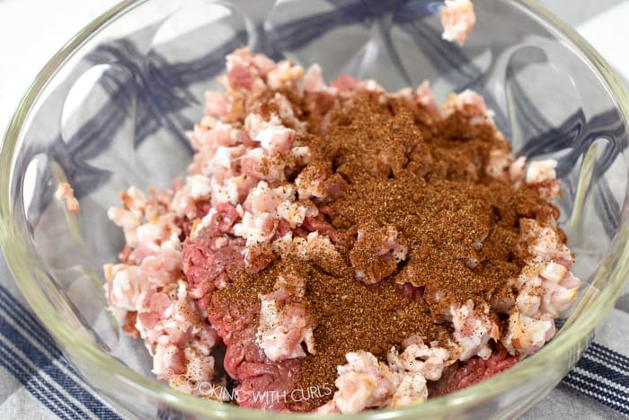 Ground beef, chopped bacon and mocha spice rub in a large glass bowl.
