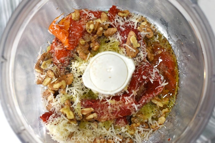 Red bell peppers, walnuts, Parmesan, olive oil, salt and pepper in the bowl of a food processor. 