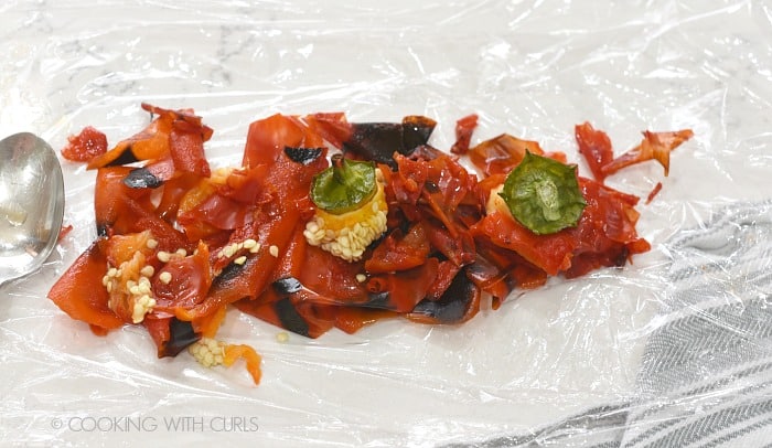 Seeds and charred skin from roasted bell peppers on plastic wrap.