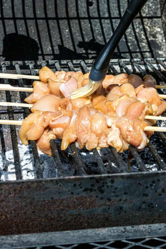 Chicken skewers on grill being cooked.