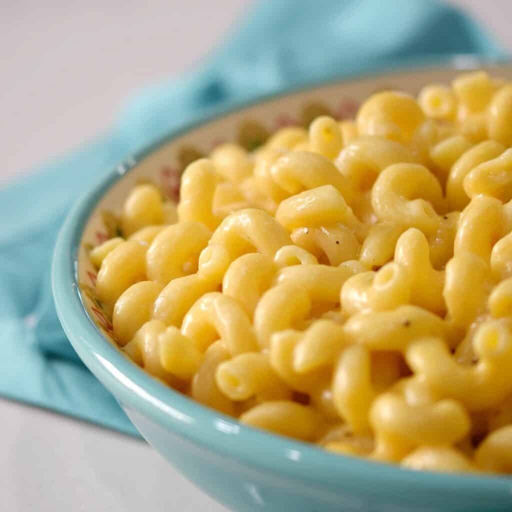 teal blue bowl filled with macaroni and cheese.
