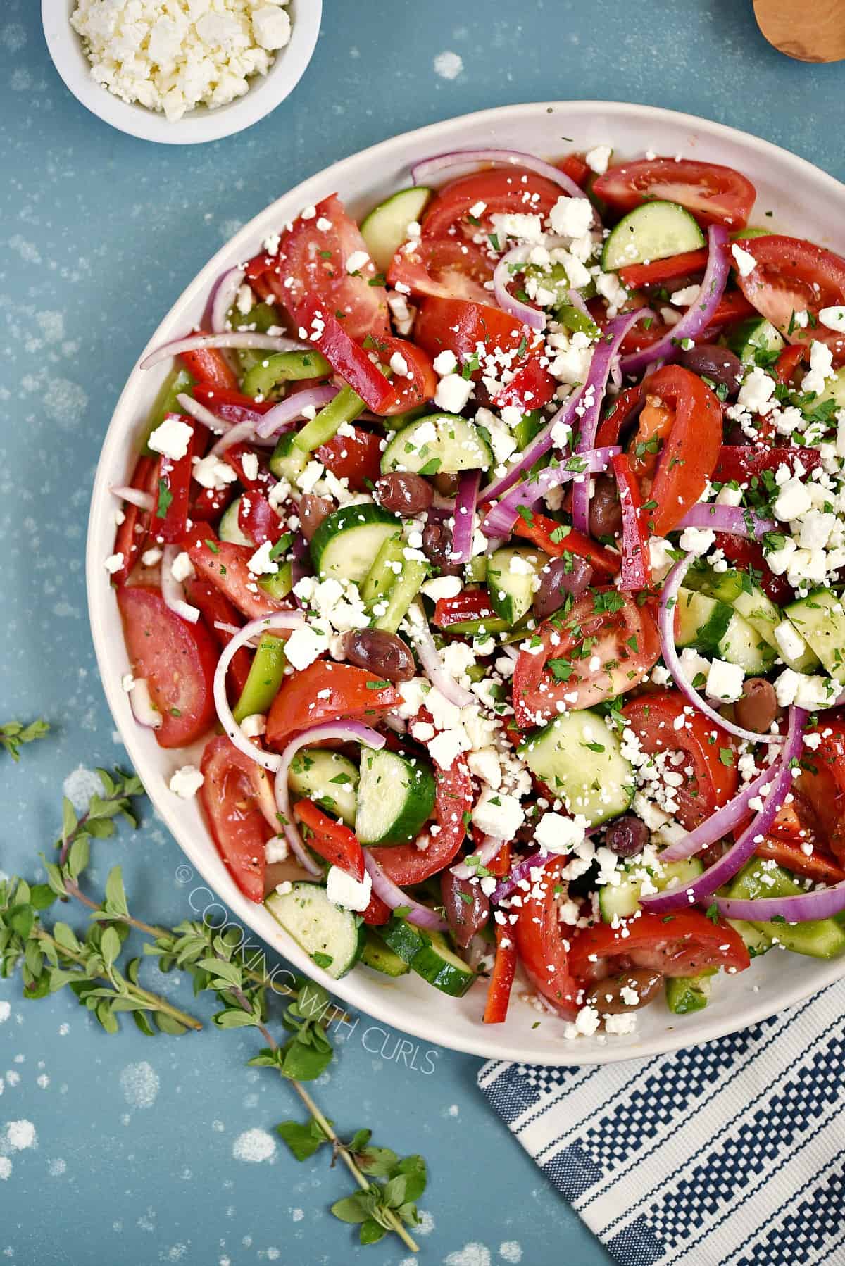 Looking down on a serving platter filled with tomato wedges, onion, bell pepper and cucumber slices sprinkled with feta cheese.