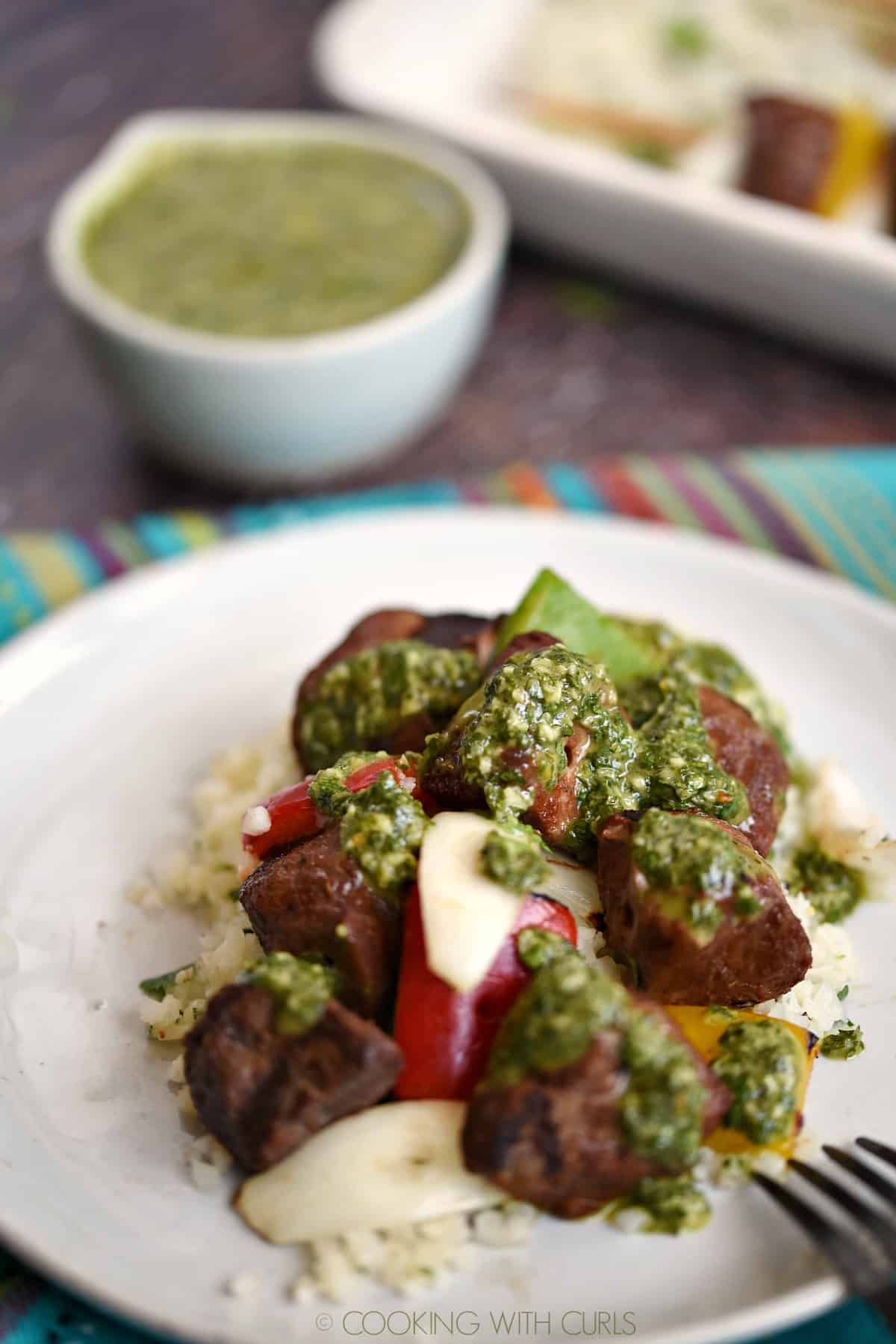 grilled steak, onion and bell peppers on a bed of rice drizzled with chimichurri sauce.