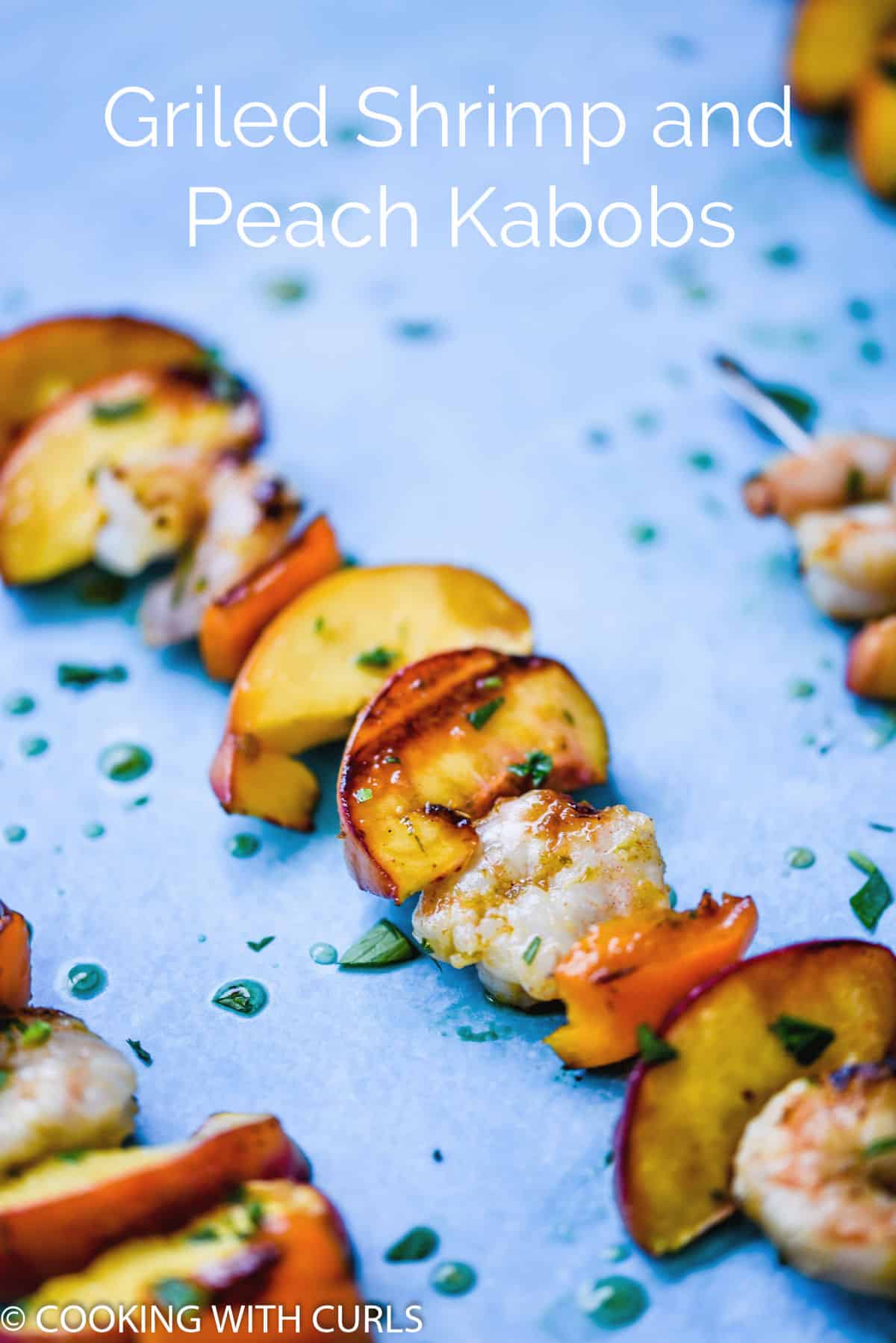 grilled shrimp and peach kabobs on metal skewers, drizzled with glaze laying on a blue background.