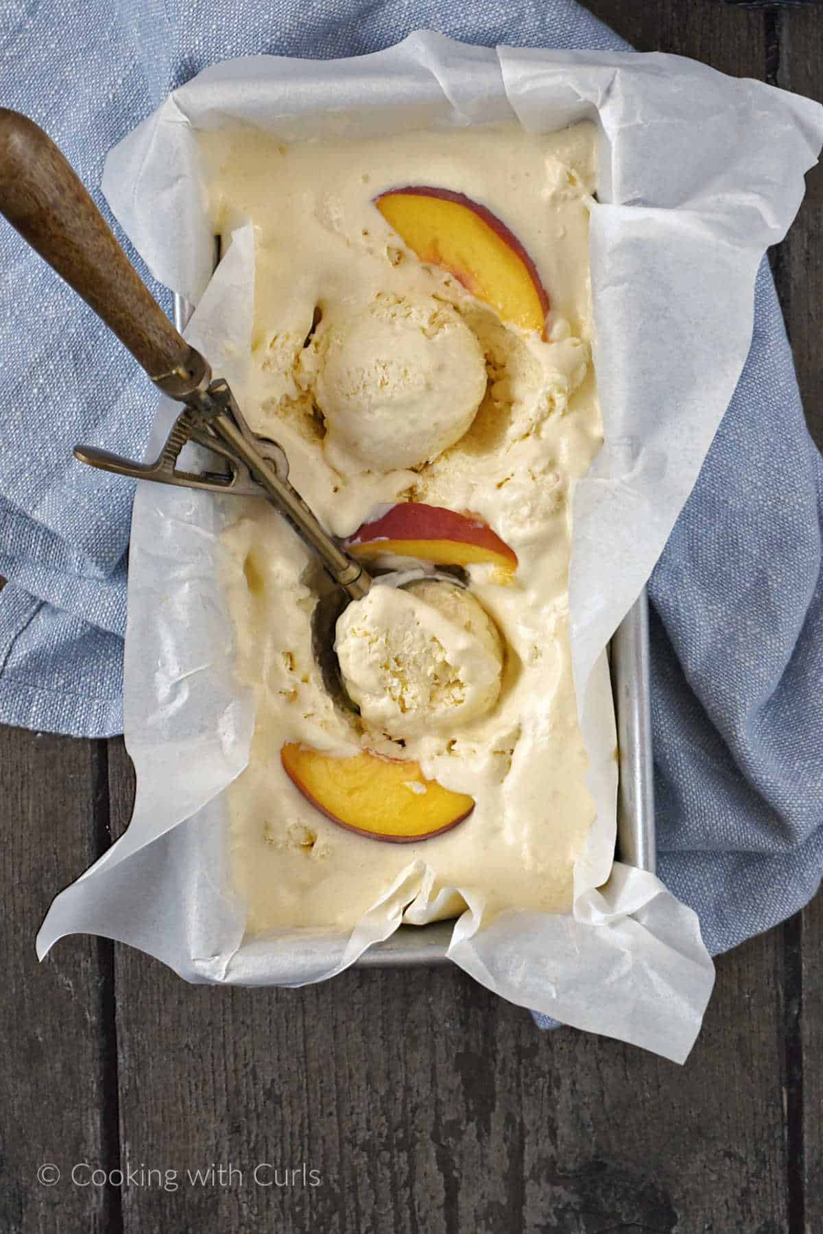 Peach ice cream in a loaf pan with parchment paper.