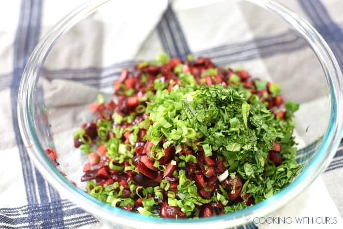 chopped cherries, green onions and cilantro in a clear glass bowl. 