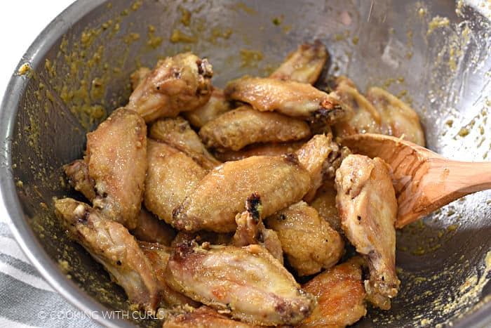 chicken wings tossed with garlic lemon sauce in a stainless steel bowl. 