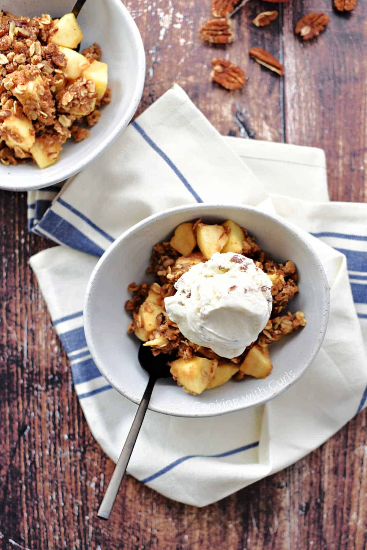A bowl of apple crisp topped with vanilla ice cream.