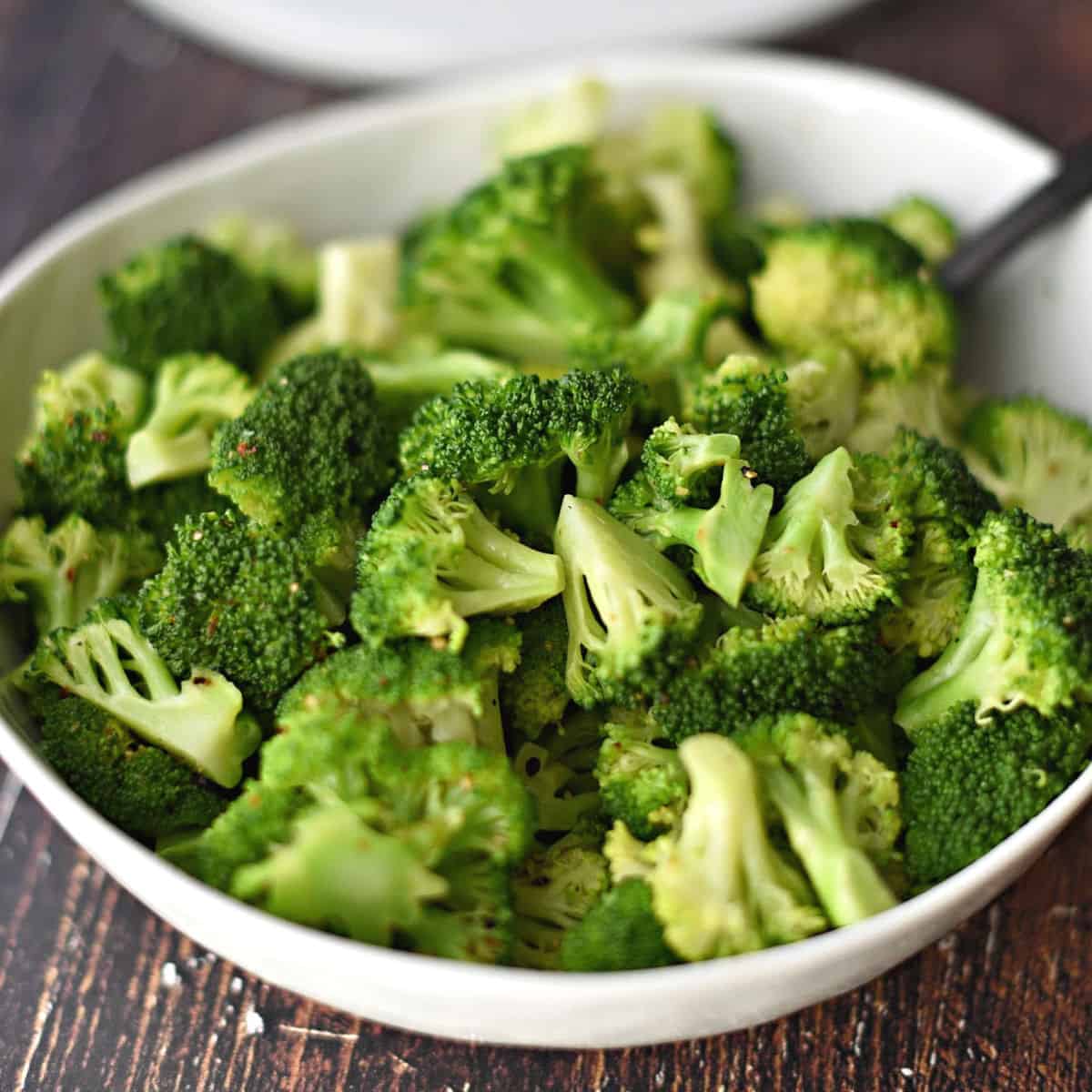 steamed broccoli in a large white bowl.