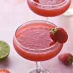 two frozen strawberry daiquiri in coupe glasses with a strawberry garnish and title graphic across the top.