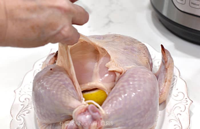 a hand lifting the skin to create a pocket between the skin and chicken breast. 