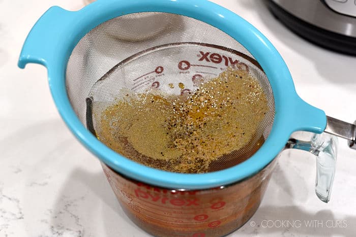 chicken stock from the pressure cooker poured through a strainer into a measuring cup. 