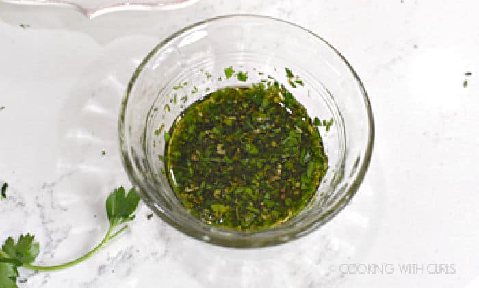 chopped parsley, thyme, oregano and oil mixed together in a small glass bowl.