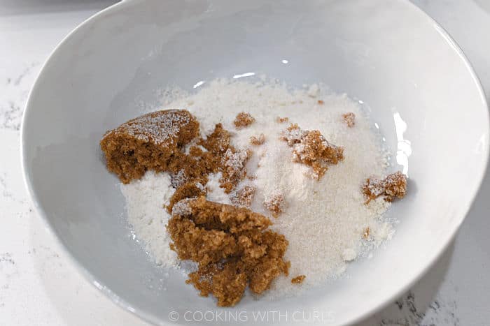 Flour, granulated and brown sugar in a white bowl. 