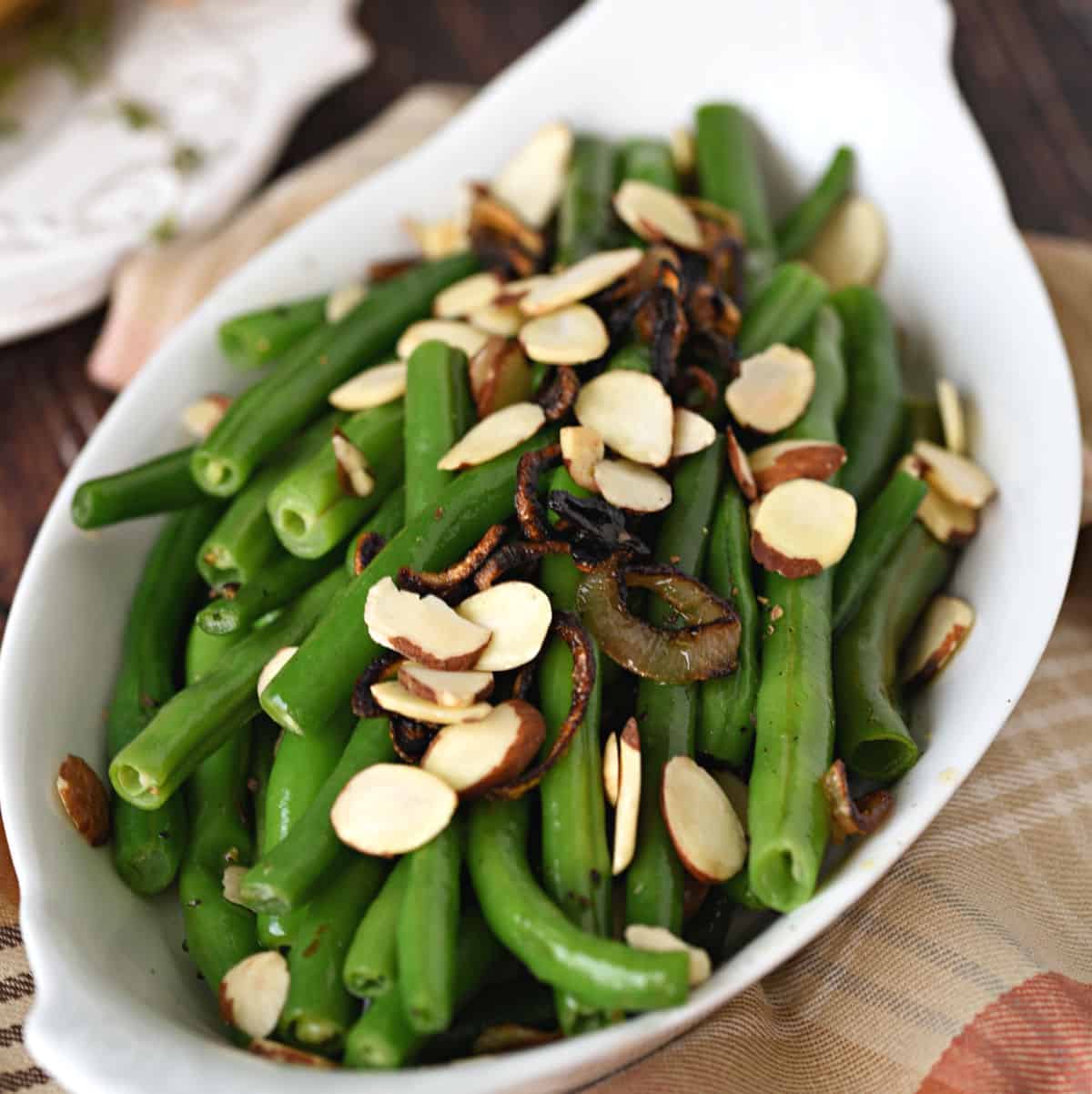 Fresh Green Beans with Caramelized Shallots and Almonds in a white au gratin dish.