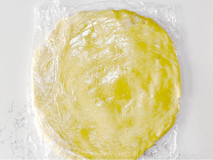 Pie crust dough circle wrapped in saran wrap. 