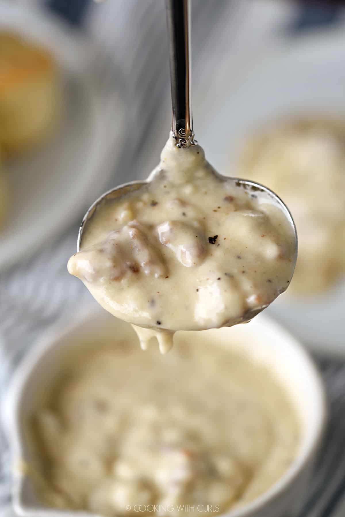 thick and creamy sausage gravy in a soup ladle over a bowl of gravy.