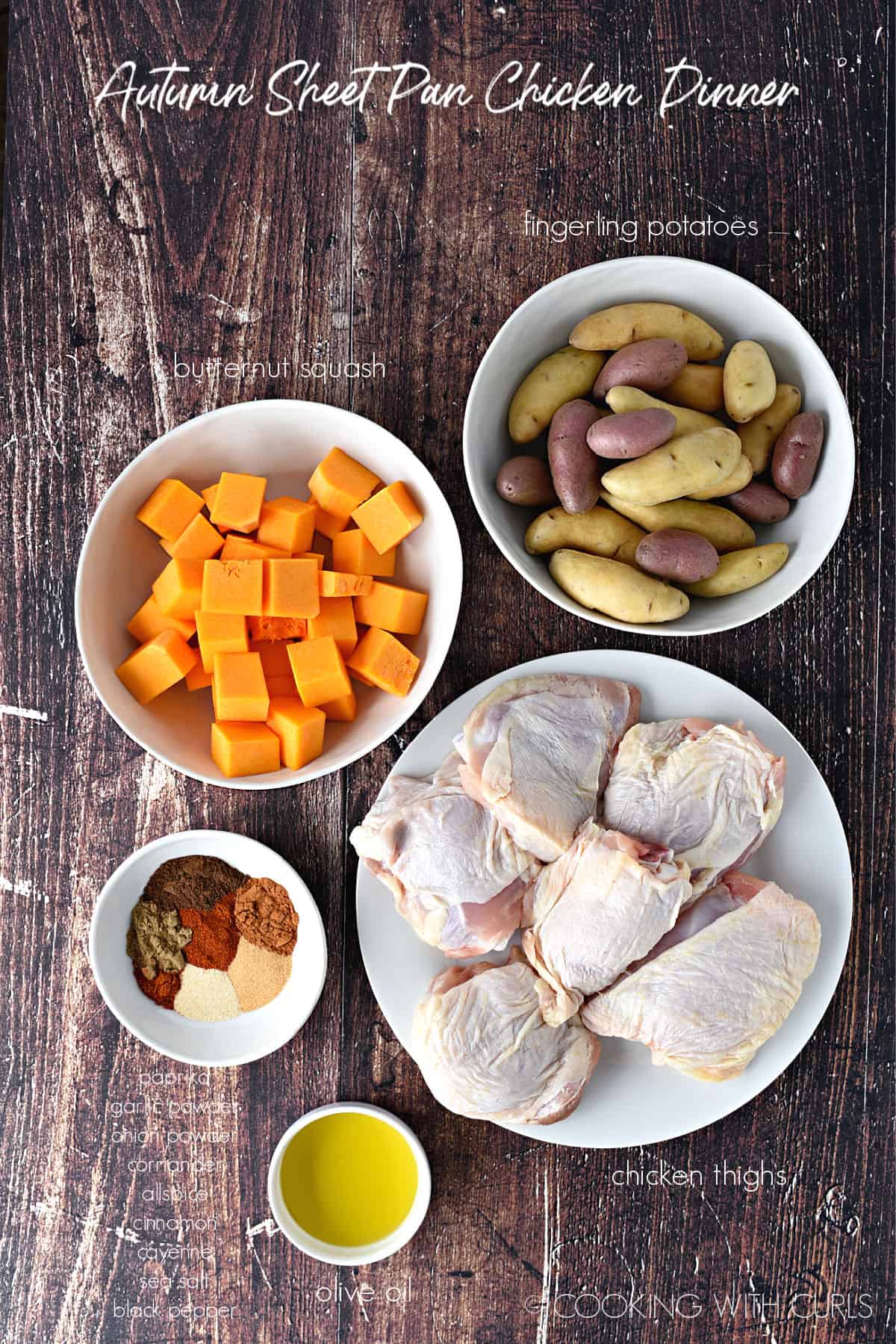 ingredients to make autumn sheet pan chicken dinner include a bowl of fingerling potatoes, a blow of butternut squash cubes, a bowl of spices, bowl of olive oil and a plate with six chicken thighs. 