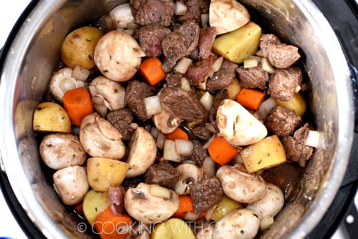Beef, mushrooms, onion, potatoes and carrots added to the wine mixture in the pressure cooker. 