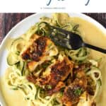 Looking down on a white plate with seasoned cod on a bed of zucchini noodle topped with a turmeric cream sauce.