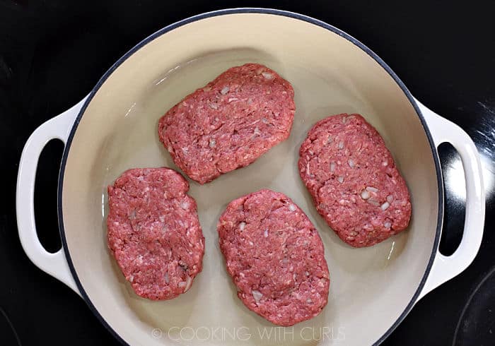 Four salisbury steaks in a cast iron skillet. 