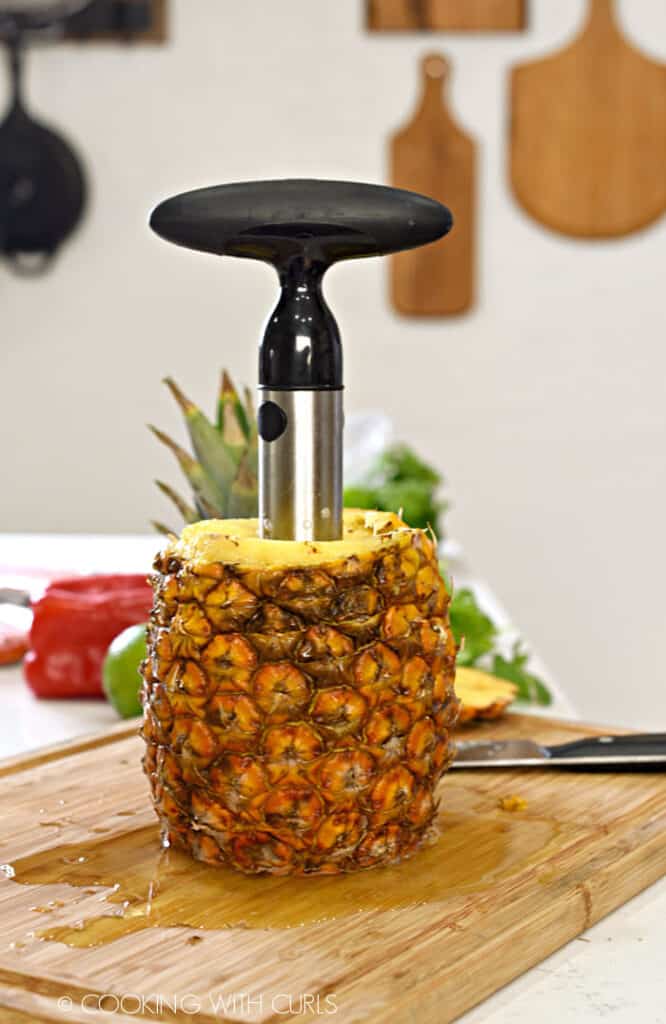 Fresh pineapple with a slicer corer tool in the center. 