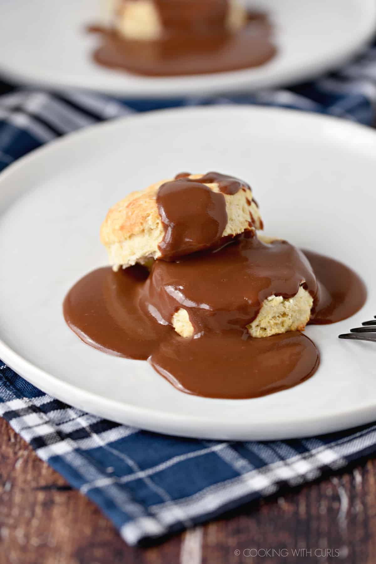 Rich, Chocolate Gravy poured over hot, Homemade Buttermilk Biscuits for a delicious breakfast treat.