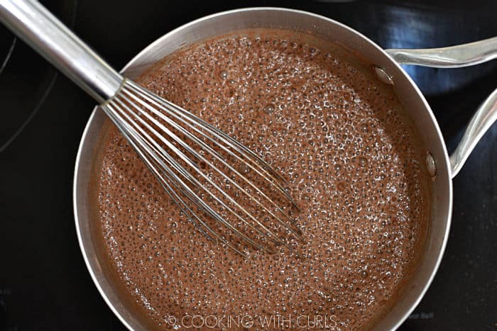 looking down on a saucepan with cocoa mixture whisked together with milk. 
