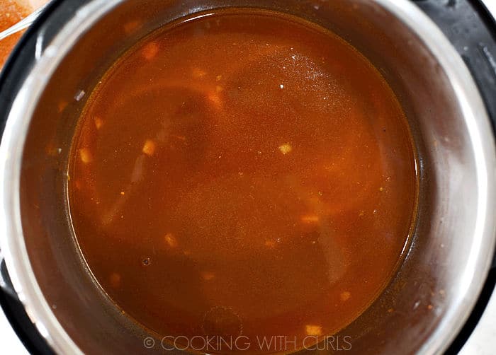 Chicken stock and enchilada sauce added to pressure cooker. 