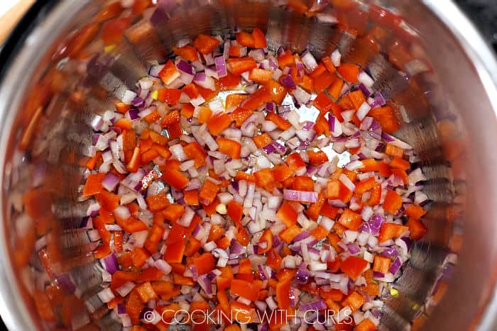 Diced red onion and red pepper in a pressure cooker. 