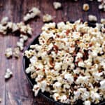 Instant Pot Chocolate Bacon Popcorn in a dark blue bowl falling out on a wooden background