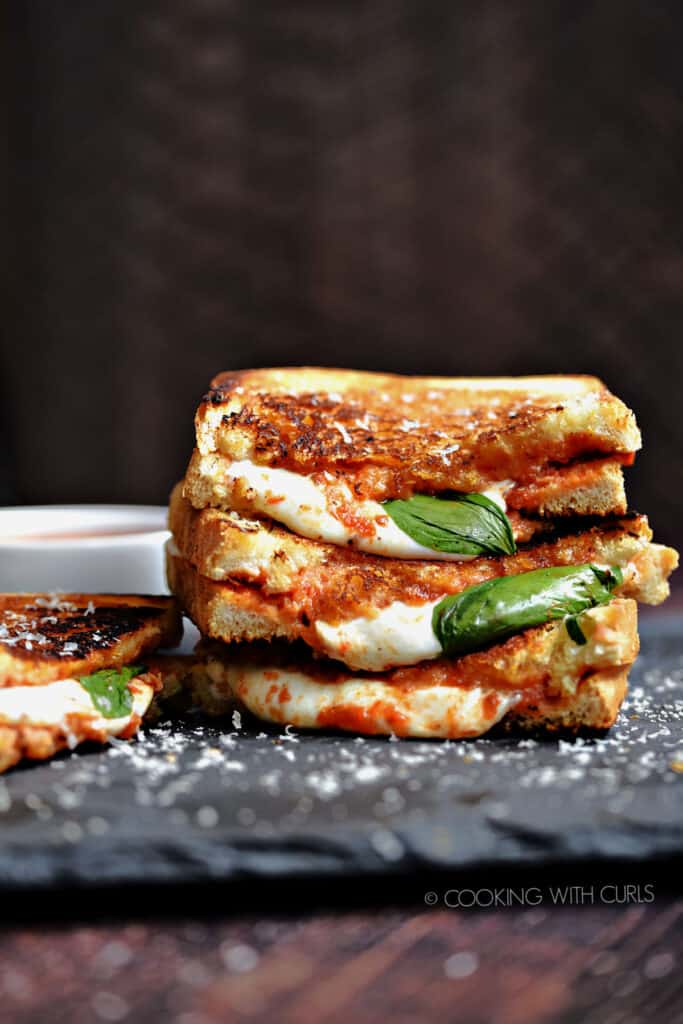 One and a half Pizza Margherita Grilled Cheese sandwiches stacked on top of each other with a fourth sitting next to the stack.