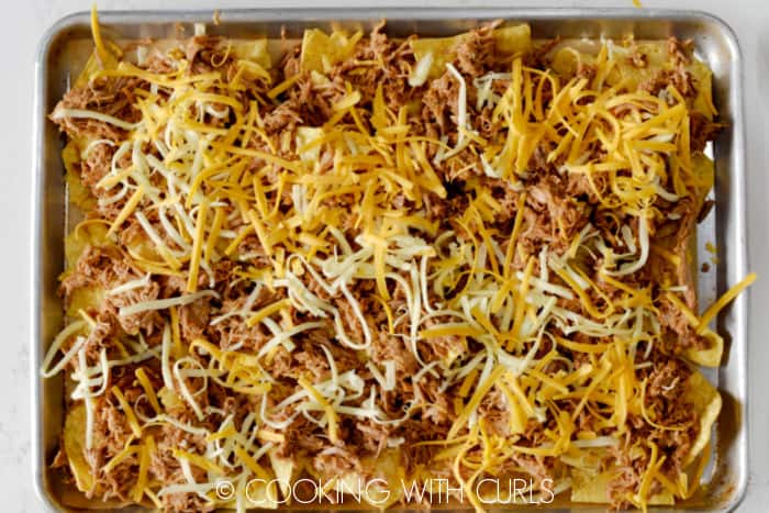 A layer of shredded cheese over the pulled pork and tortilla chips. 
