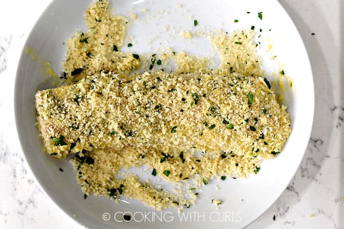 A piece of cod coated in panko crumbs on a white plate. 
