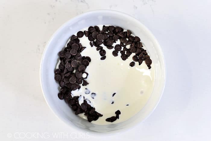 Chocolate chips and cream in a white bowl. 